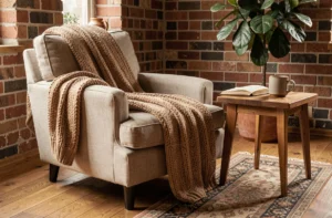 Coin salon chaleureux avec fauteuil en lin, plaid tricoté et table en bois dans un intérieur décoré avec des tons terre